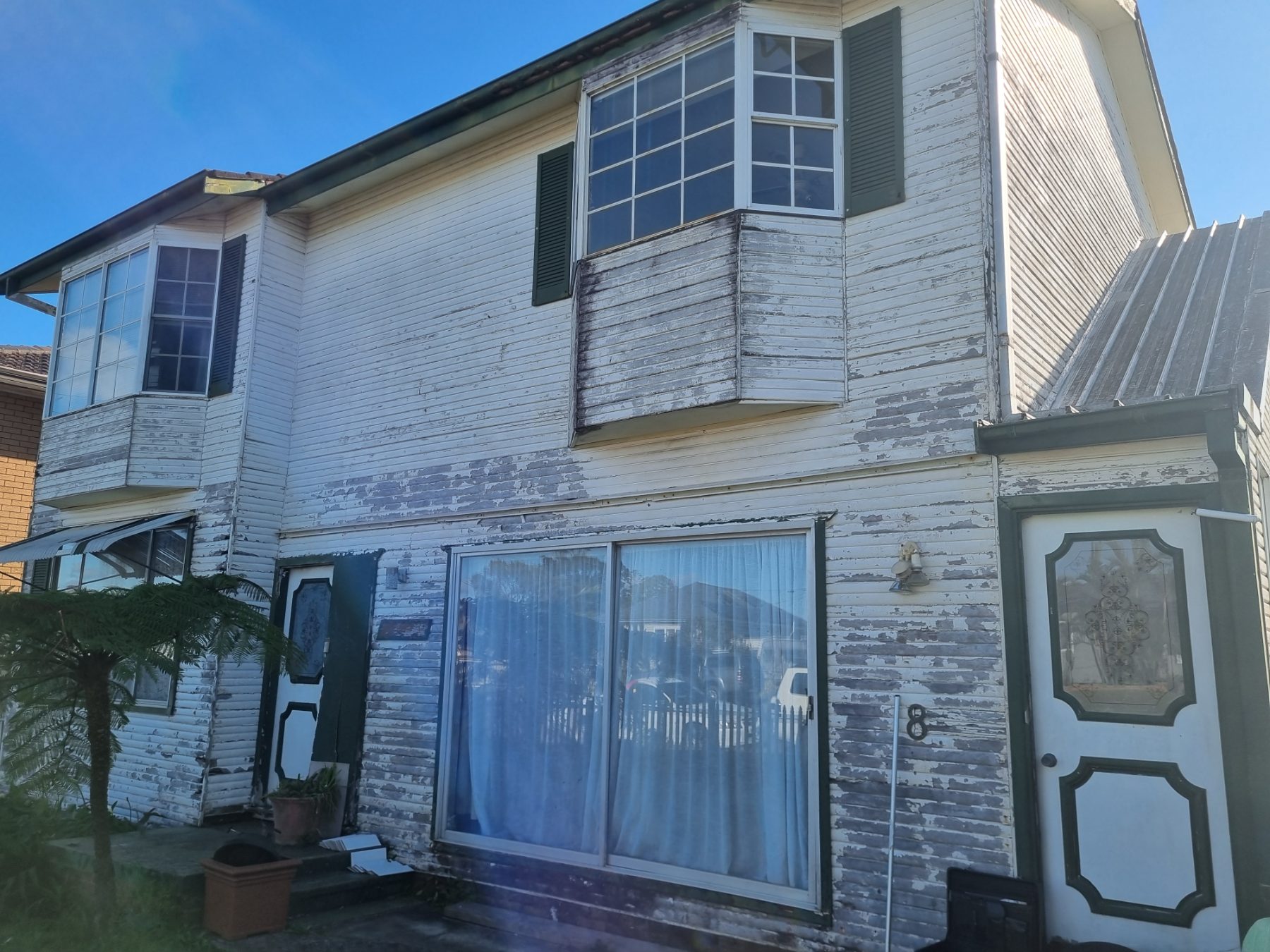 Before: Two-storey home re-clad in grey vinyl weatherboards